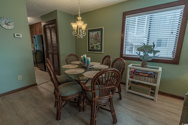 dining space featuring a chandelier, light hardwood / wood-style floors, and a textured ceiling