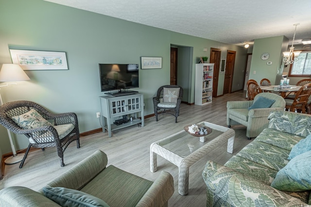 living room featuring a textured ceiling, light hardwood / wood-style floors, and a chandelier