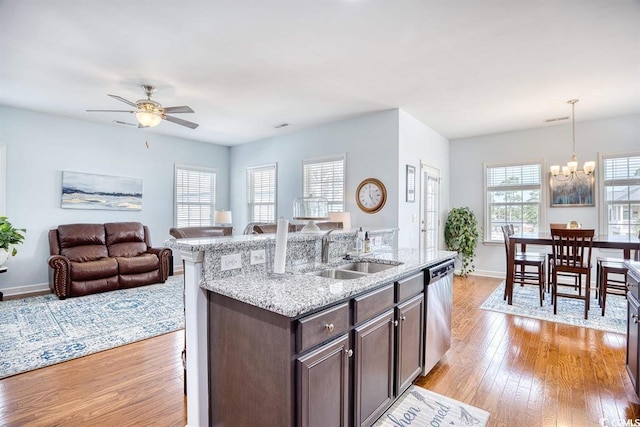 kitchen with dark brown cabinets, light hardwood / wood-style floors, sink, ceiling fan with notable chandelier, and decorative light fixtures