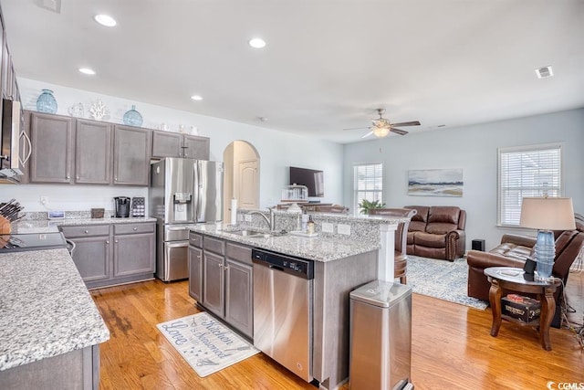 kitchen with a healthy amount of sunlight, ceiling fan, appliances with stainless steel finishes, and a kitchen island with sink