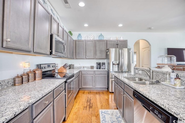 kitchen featuring light hardwood / wood-style floors, sink, stainless steel appliances, and light stone counters