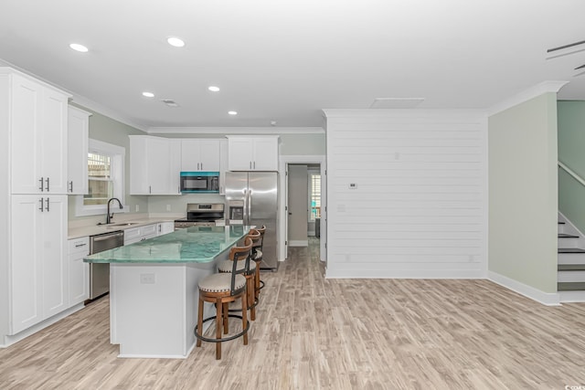 kitchen featuring a sink, a kitchen island, ornamental molding, and stainless steel appliances