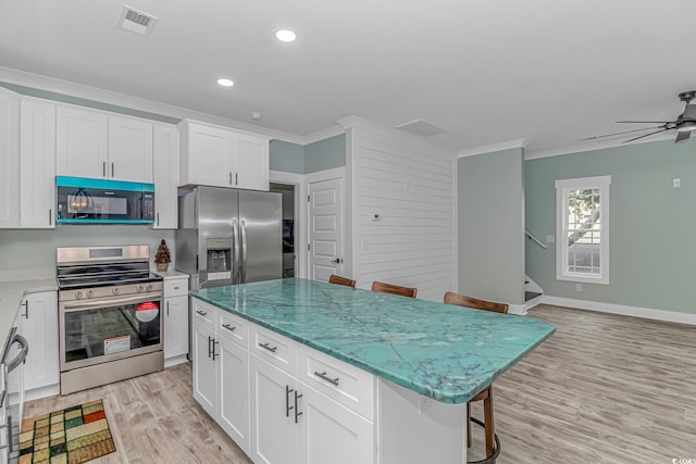 kitchen featuring a kitchen island, light hardwood / wood-style flooring, stainless steel appliances, a breakfast bar area, and crown molding