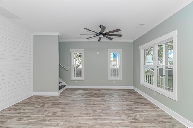 unfurnished room with wooden walls, crown molding, light wood-type flooring, and ceiling fan