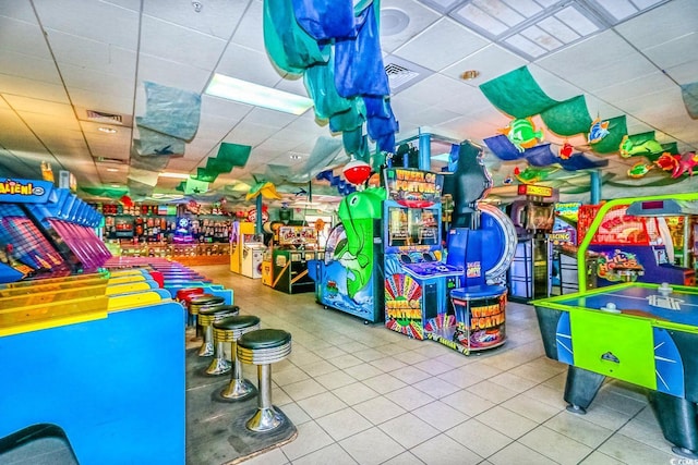 game room with a drop ceiling and tile patterned flooring