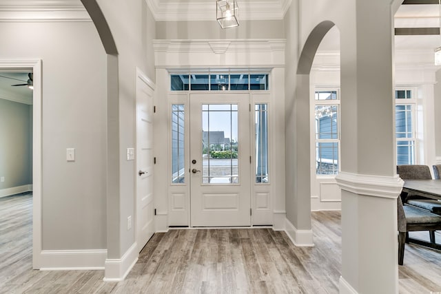 entrance foyer featuring light hardwood / wood-style flooring, ornate columns, ceiling fan, and crown molding