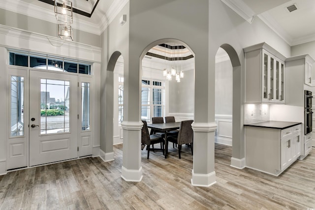 entrance foyer with a notable chandelier, plenty of natural light, light hardwood / wood-style floors, and crown molding