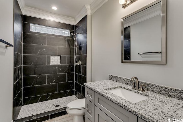 bathroom featuring tiled shower, crown molding, vanity, and toilet