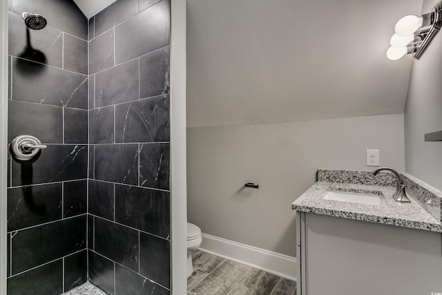 bathroom with tiled shower, hardwood / wood-style flooring, vanity, and toilet