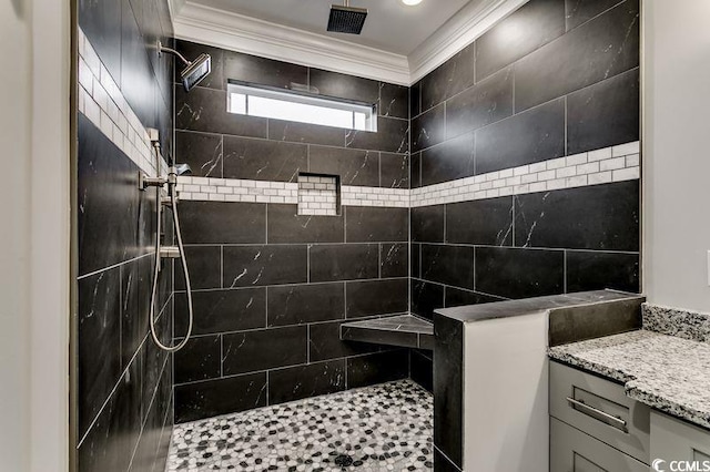 bathroom with ornamental molding, vanity, and tiled shower