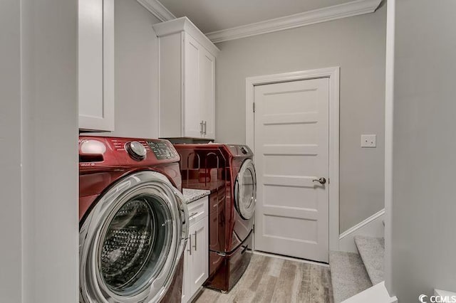 laundry area featuring washer and clothes dryer, crown molding, light hardwood / wood-style flooring, and cabinets