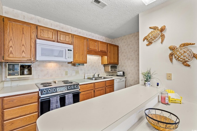 kitchen with a textured ceiling, sink, and white appliances