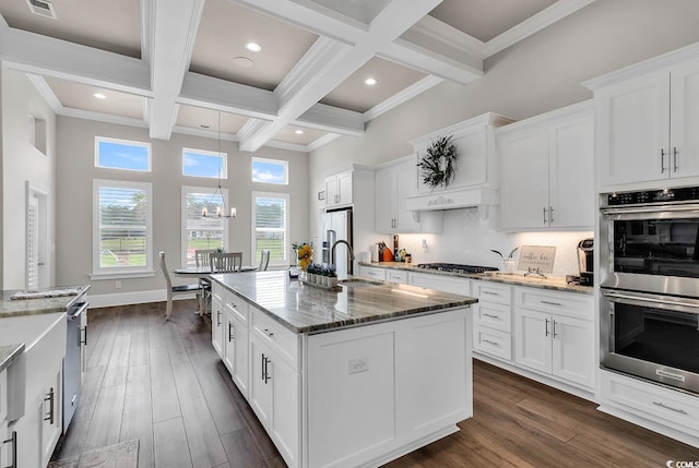 kitchen with white cabinets, an island with sink, dark hardwood / wood-style floors, and stone countertops