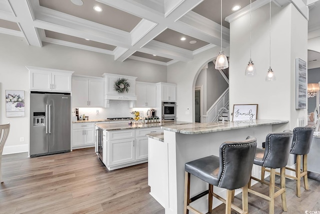 kitchen featuring white cabinets, stainless steel appliances, kitchen peninsula, and light stone countertops