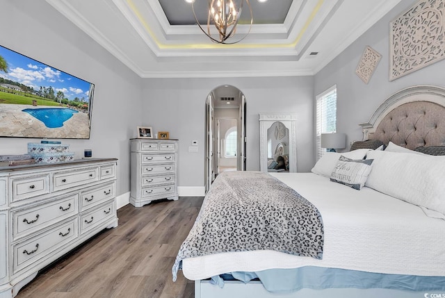 bedroom featuring a raised ceiling, ornamental molding, dark hardwood / wood-style flooring, and a notable chandelier