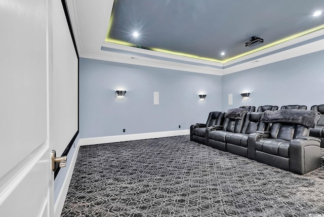 carpeted home theater room with a raised ceiling and ornamental molding