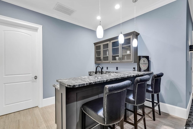 kitchen featuring light wood-type flooring, kitchen peninsula, and decorative light fixtures