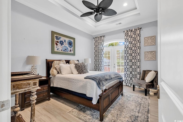 bedroom featuring ornamental molding, light wood-type flooring, a tray ceiling, and ceiling fan