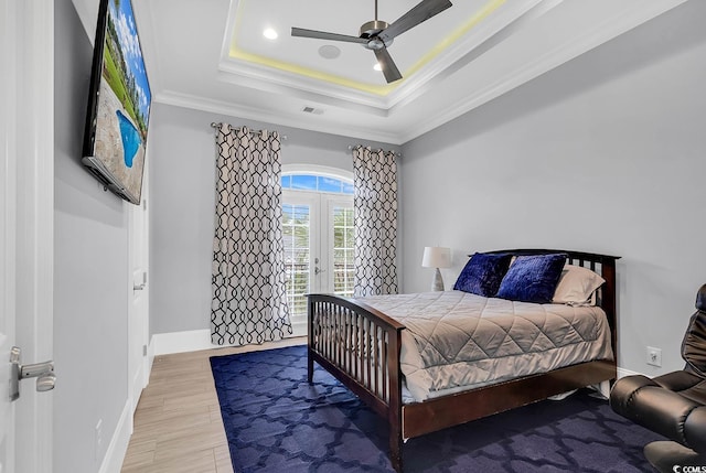 bedroom with ceiling fan, light hardwood / wood-style flooring, ornamental molding, and a tray ceiling