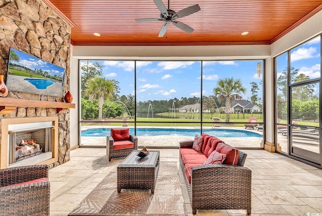 sunroom / solarium with a pool, ceiling fan, wooden ceiling, and a stone fireplace