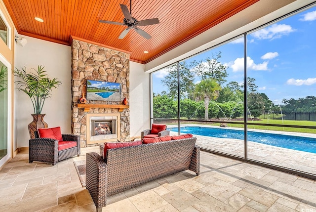 sunroom / solarium with wood ceiling, ceiling fan, and a fireplace