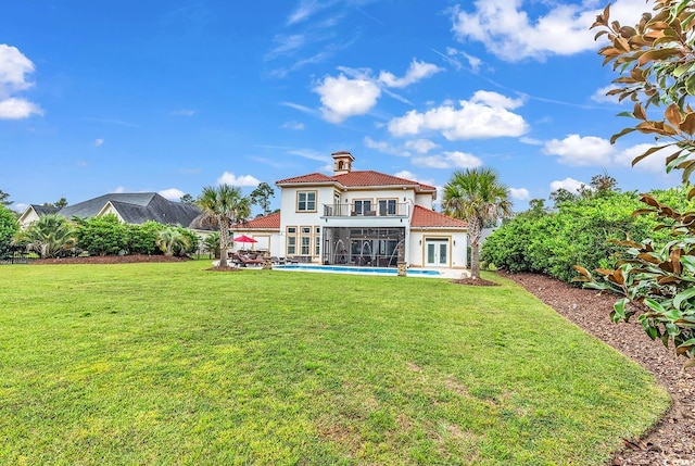 rear view of property featuring a balcony, a yard, and a patio area