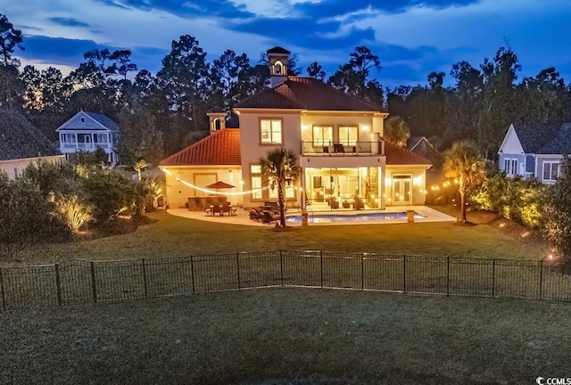 view of front of house featuring a balcony, a yard, and a patio area