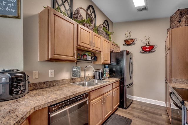 kitchen with appliances with stainless steel finishes, light hardwood / wood-style floors, sink, and light brown cabinets