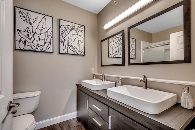 bathroom featuring hardwood / wood-style flooring, a shower with door, vanity, and toilet