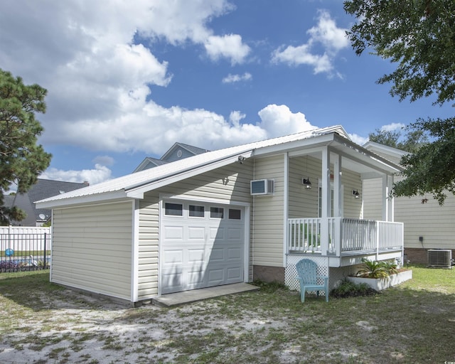 exterior space with a porch, a garage, a wall mounted AC, and central air condition unit