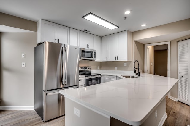 kitchen with light hardwood / wood-style flooring, white cabinetry, appliances with stainless steel finishes, and sink