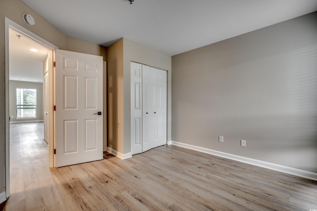 unfurnished bedroom with light wood-type flooring and a closet