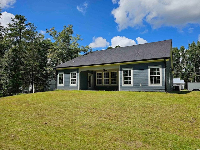 rear view of house featuring ceiling fan and a yard