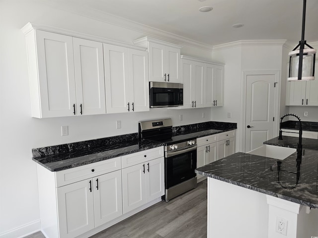 kitchen with appliances with stainless steel finishes, hanging light fixtures, light hardwood / wood-style floors, white cabinets, and crown molding