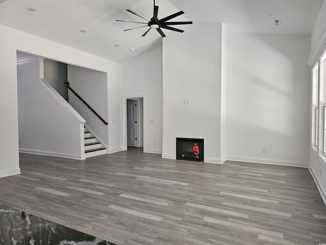 unfurnished living room with wood-type flooring, ceiling fan, and high vaulted ceiling