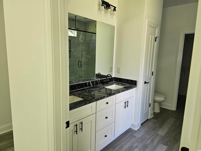 bathroom with wood-type flooring, a shower with door, vanity, and toilet