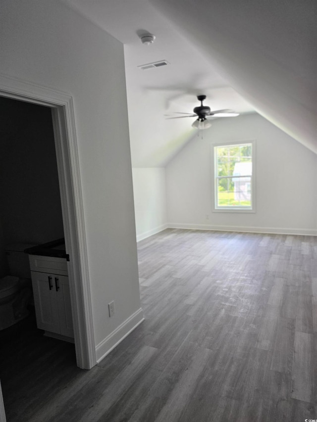 additional living space with vaulted ceiling, dark wood-type flooring, and ceiling fan