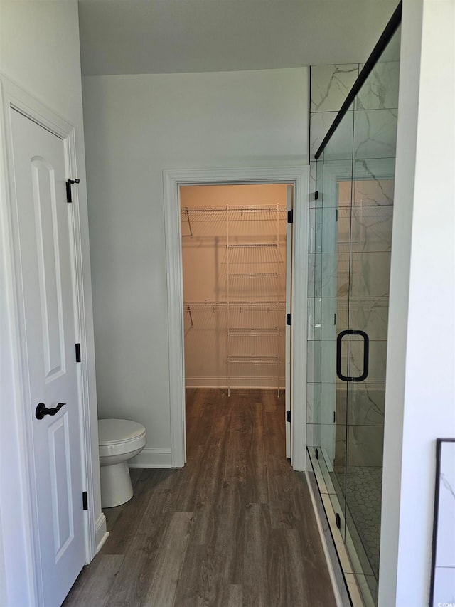 bathroom with walk in shower, hardwood / wood-style flooring, and toilet