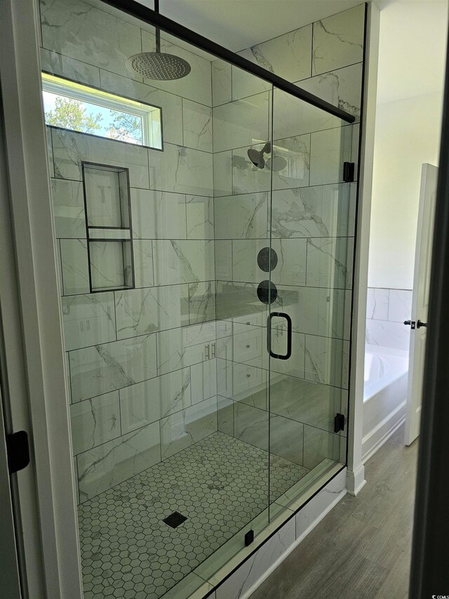 bathroom with independent shower and bath and wood-type flooring