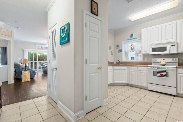 1100 Commons Blvd Unit 104, Myrtle Beach, SC 29572 - kitchen with white appliances, light tile patterned flooring, white cabinetry, crown molding, and a textured ceiling