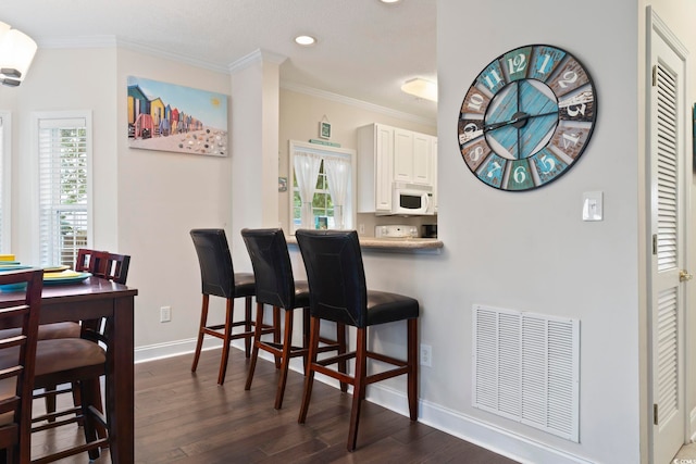 1100 Commons Blvd Unit 104, Myrtle Beach, SC 29572 - kitchen with white microwave, a kitchen breakfast bar, dark wood finished floors, plenty of natural light, and crown molding
