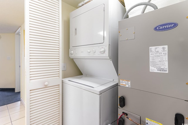 laundry room featuring heating unit, light tile patterned floors, and stacked washing maching and dryer