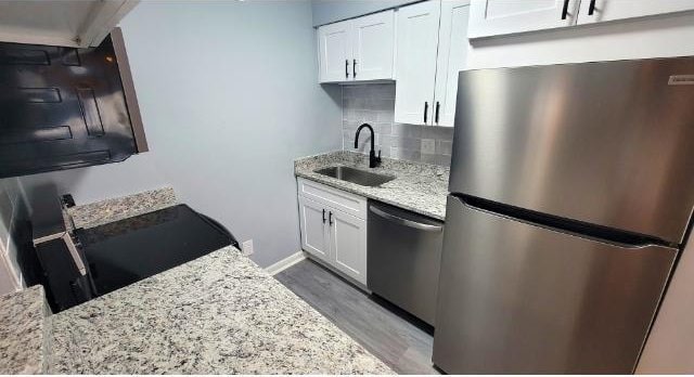 10166 Beach Dr Unit 5306, Calabash, NC 28467 - kitchen featuring appliances with stainless steel finishes, a sink, light wood finished floors, light stone counters, and decorative backsplash