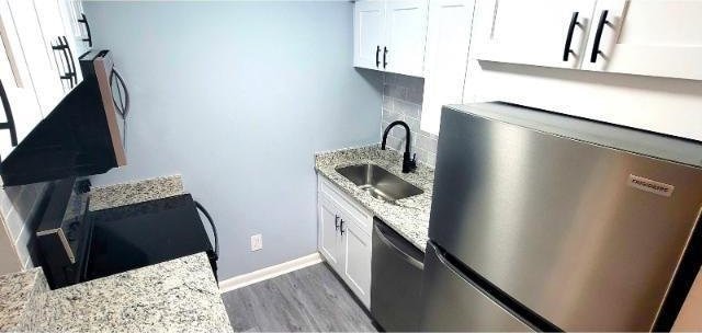 10166 Beach Dr Unit 5306, Calabash, NC 28467 - kitchen featuring a sink, dishwashing machine, wood finished floors, stainless steel fridge, and white cabinetry