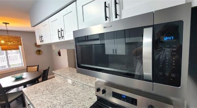 10166 Beach Dr Unit 5306, Calabash, NC 28467 - kitchen with stainless steel microwave, decorative light fixtures, white cabinets, and oven