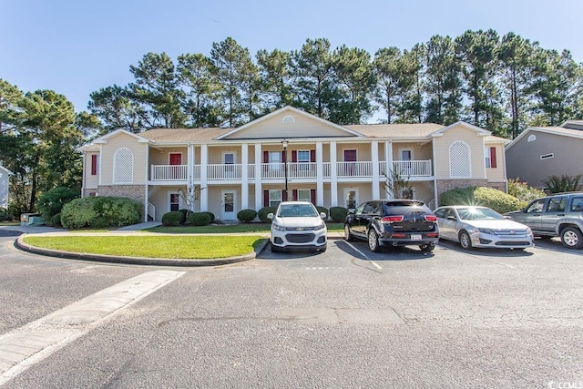 view of front of property featuring a front yard and a balcony