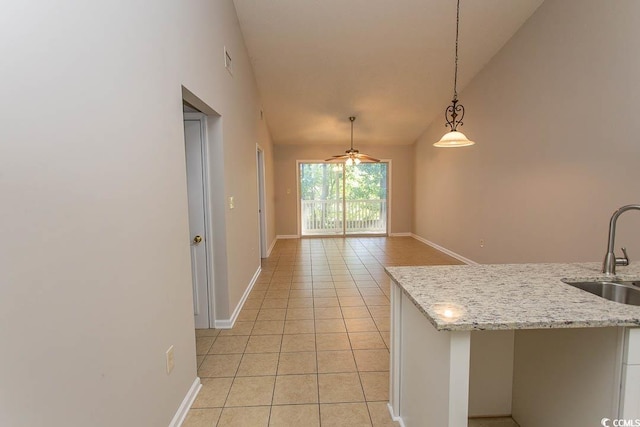 kitchen with sink, light stone countertops, vaulted ceiling, pendant lighting, and ceiling fan