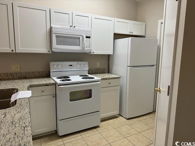 kitchen with white cabinets, light stone counters, white appliances, and light tile patterned floors