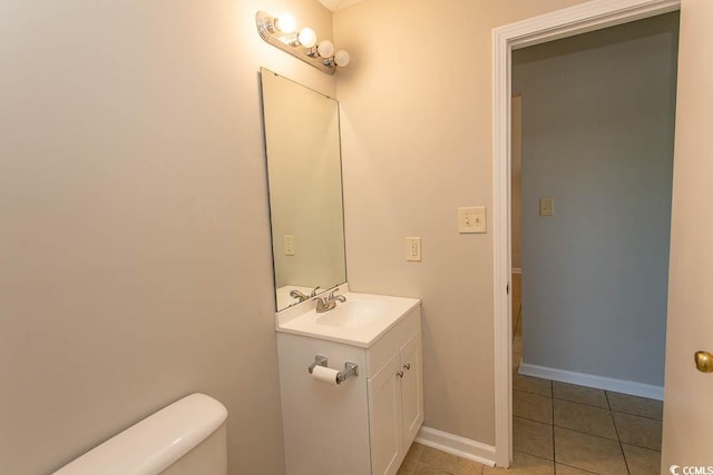 bathroom with toilet, vanity, and tile patterned flooring