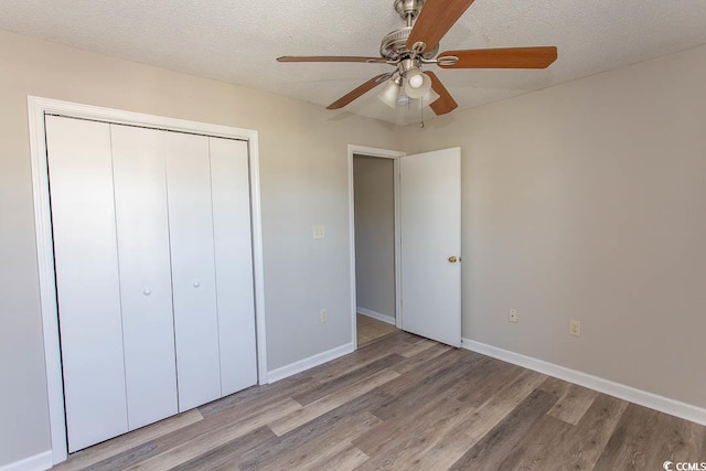 unfurnished bedroom featuring a closet, a textured ceiling, hardwood / wood-style flooring, and ceiling fan